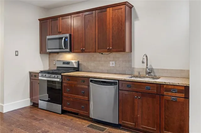 a kitchen with kitchen island granite countertop wooden cabinets and stainless steel appliances