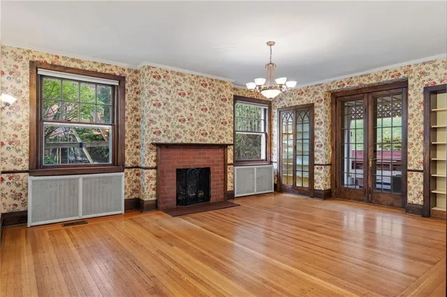 a view of an empty room with window and wooden floor