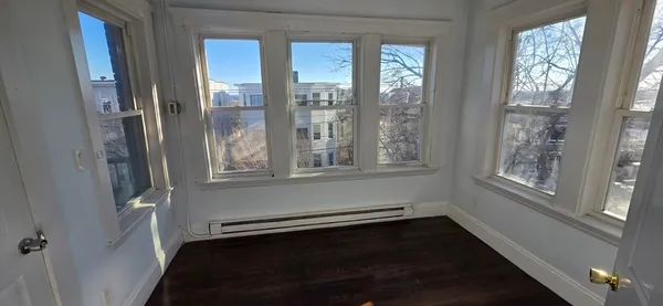 a view of an empty room with a window and wooden floor
