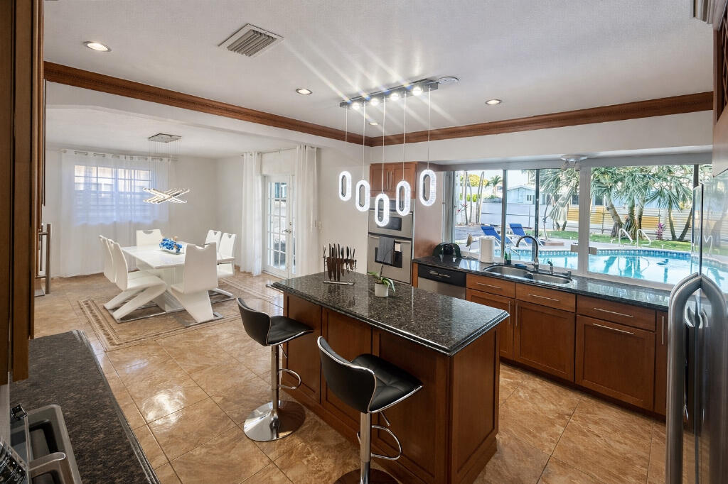 5408 Jackson Street Hollywood, FL 33021 - Photo 15 of 42 a dining hall with stainless steel appliances granite countertop a stove a sink a dining table and chairs with the floor to the kitchen