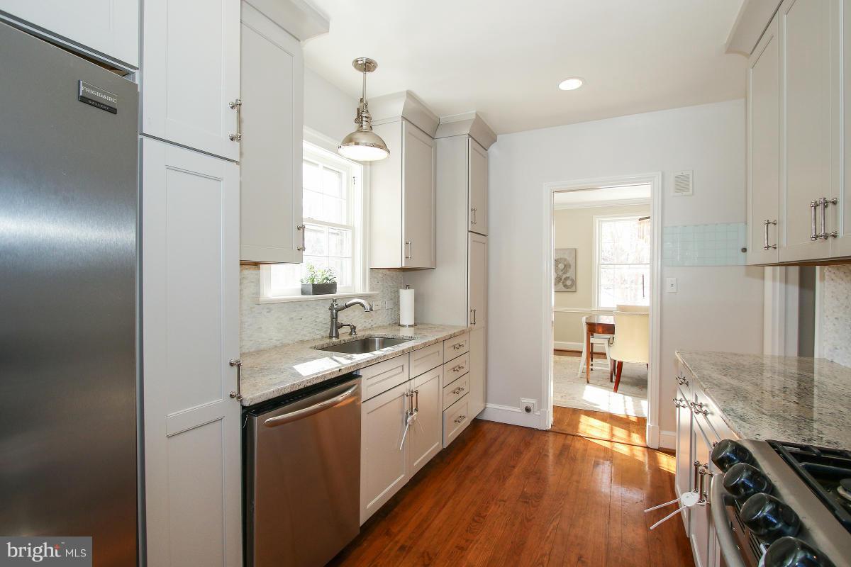 3231 Rittenhouse Street Northwest Washington, DC 20015 - Photo 12 of 27 a kitchen with a sink dishwasher a stove and white cabinets with wooden floor