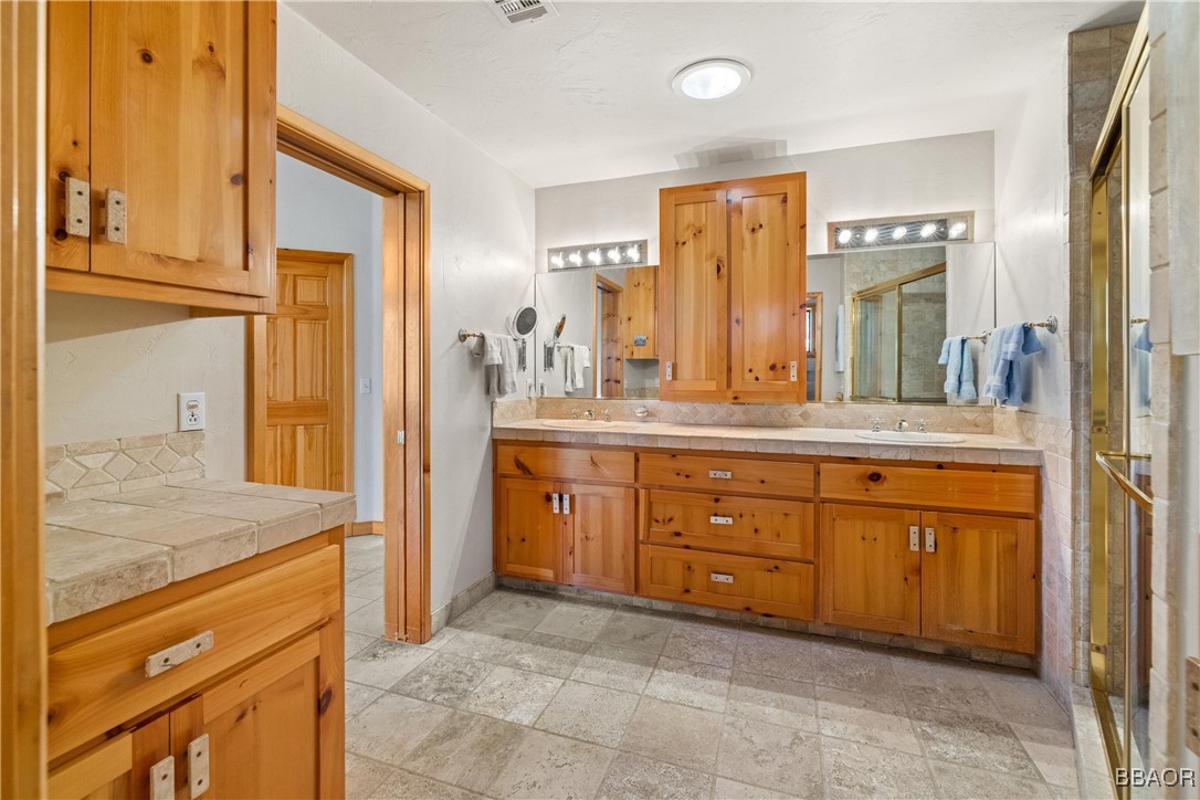 39585 Lakeview Pines Road Big Bear Lake, CA 92315 - Photo 34 of 49 a spacious bathroom with a granite countertop sink and a mirror