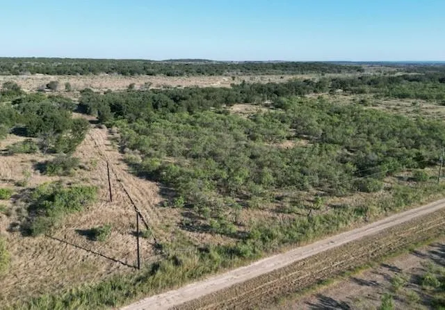 a view of a field with an ocean and trees