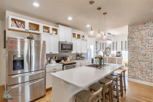a kitchen with stainless steel appliances kitchen island granite countertop a refrigerator a stove a sink dishwasher with a dining table and chairs