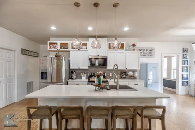 a kitchen with stainless steel appliances granite countertop a dining table chairs and refrigerator