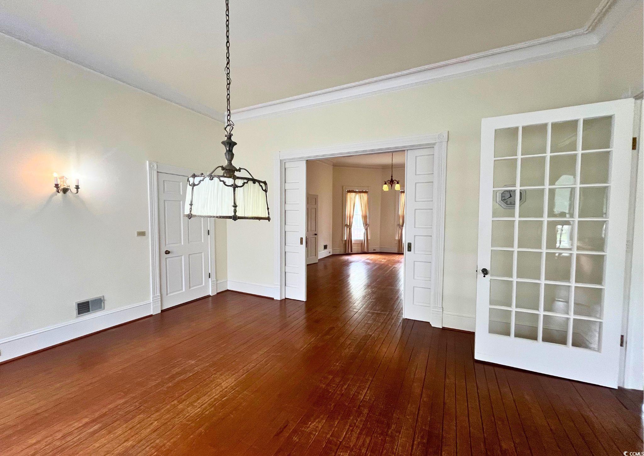 309 North Academy Street Kingstree, SC 29556 - Photo 10 of 38 Unfurnished dining area with ornamental molding, dark wood-style flooring, and a chandelier