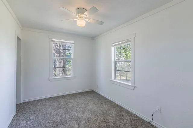 an empty room with windows and fan