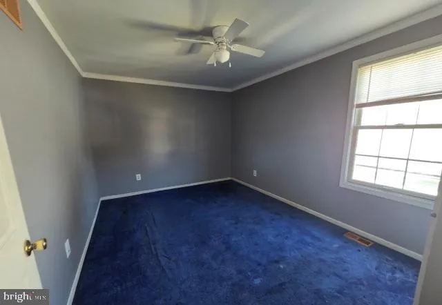 an empty room with a window and a ceiling fan