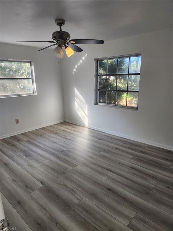 200 Willoughby Drive Naples, FL 34110 - Photo 12 of 15 Empty room with ceiling fan, a healthy amount of sunlight, and dark hardwood / wood-style floors