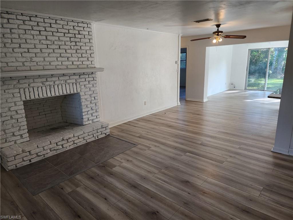 200 Willoughby Drive Naples, FL 34110 - Photo 3 of 15 Unfurnished living room featuring dark hardwood / wood-style floors, a brick fireplace, and ceiling fan