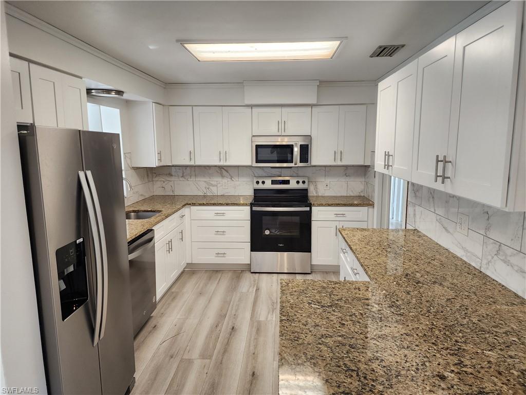 200 Willoughby Drive Naples, FL 34110 - Photo 4 of 15 Kitchen with stone counters, white cabinetry, and stainless steel appliances