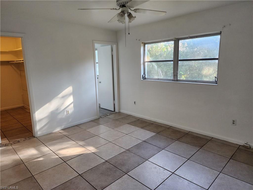 200 Willoughby Drive Naples, FL 34110 - Photo 5 of 15 Unfurnished bedroom featuring ceiling fan, light tile patterned flooring, a walk in closet, and a closet