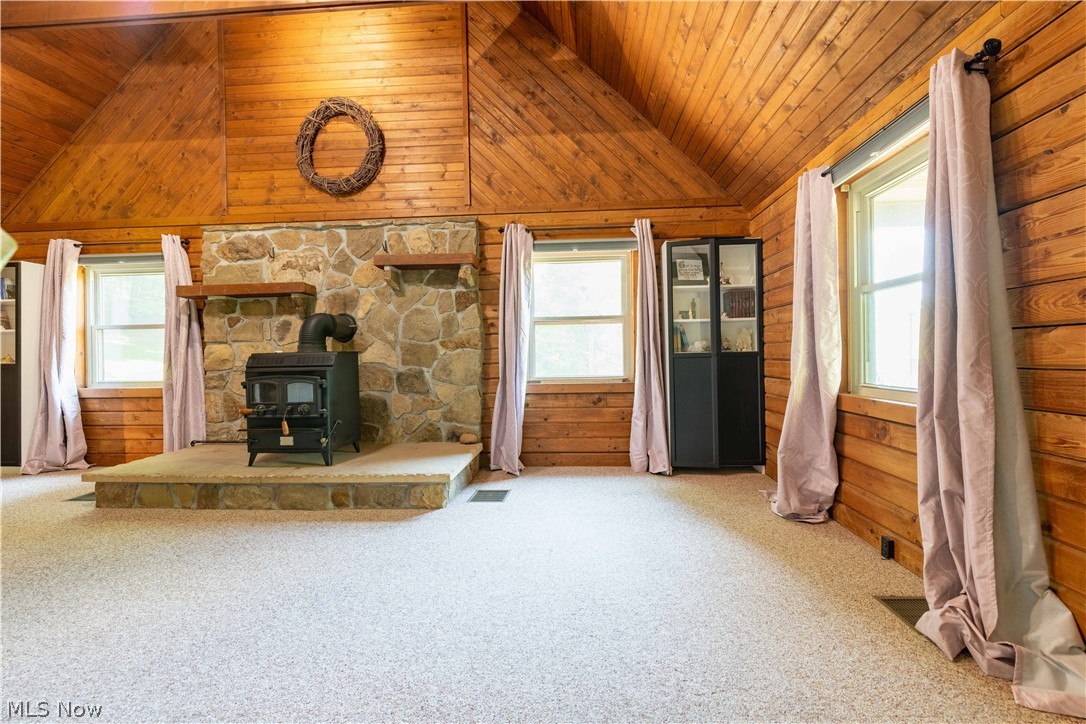 36048 South 16 Road Barnesville, OH 43713 - Photo 23 of 45 Unfurnished living room featuring wooden ceiling, a healthy amount of sunlight, and a wood stove