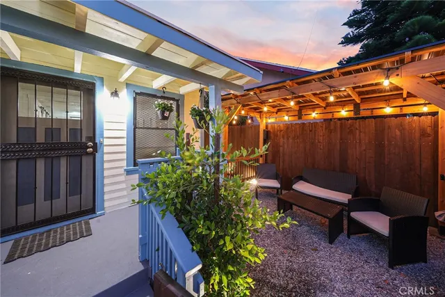 a backyard of a house with wooden chairs and a table