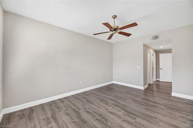 an empty room with wooden floor a ceiling fan and a window