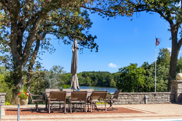 a view of a patio with table and chairs potted plants and a large tree