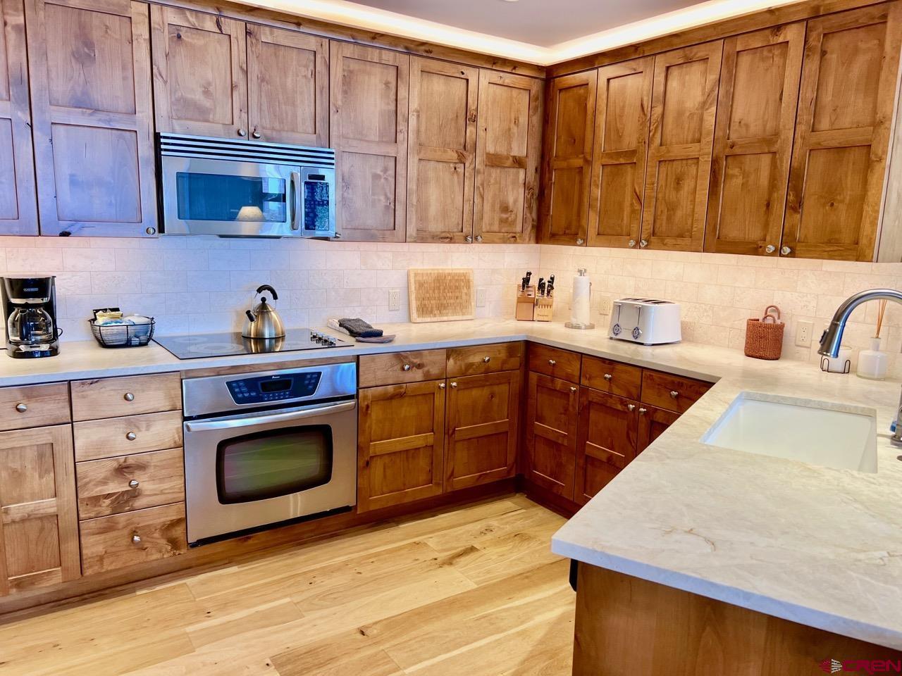 14 Hunter Hill Road, Unit C203 Crested Butte, CO 81225 - Photo 12 of 34 a kitchen with stainless steel appliances granite countertop a sink dishwasher stove and cabinets with wooden floor