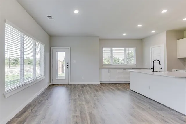 a view of a kitchen that shows a sink dishwasher and wooden floor