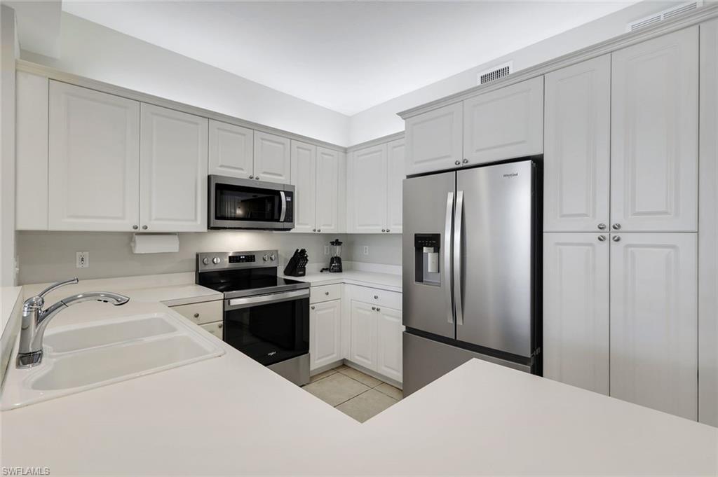 460 Launch Circle, Unit 202 Naples, FL 34108 - Photo 9 of 34 a kitchen with a refrigerator sink and white cabinets