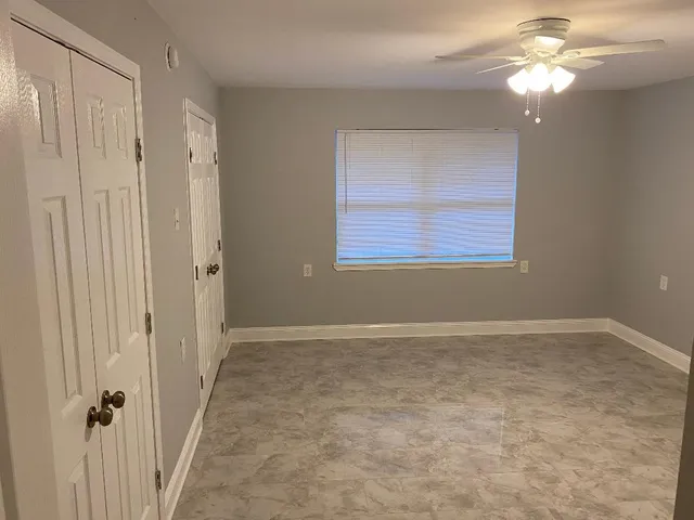 an empty room with windows and fan