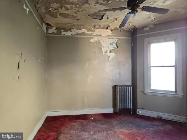 an empty room with windows and ceiling fan