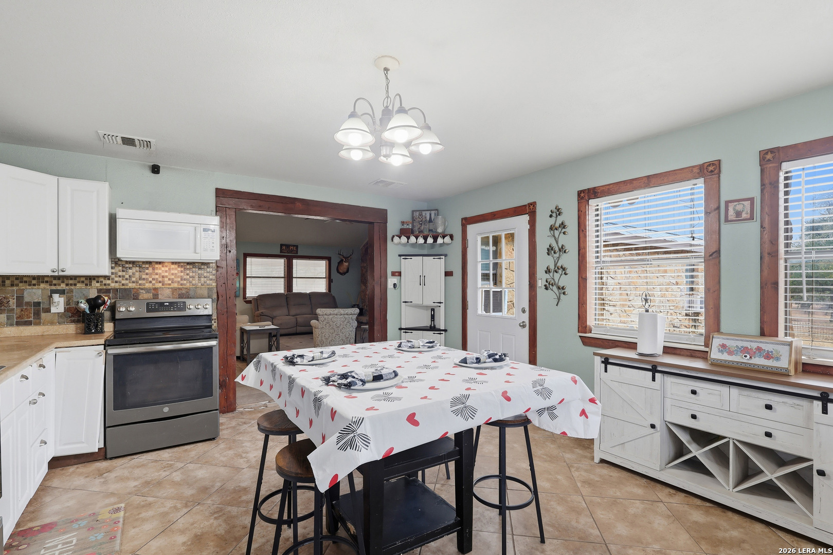 31910 Blanco Road Bulverde, TX 78163 - Photo 9 of 25 a kitchen with stainless steel appliances kitchen island granite countertop a stove a sink dishwasher a dining table and chairs with wooden floor