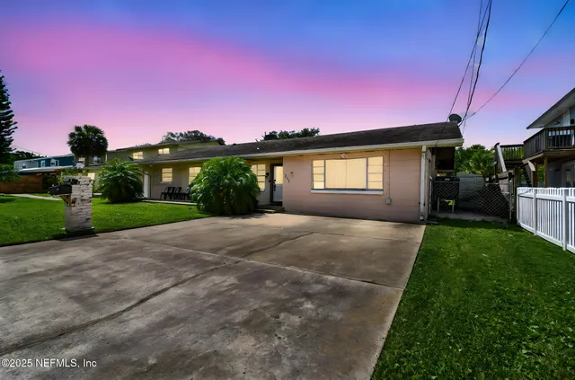 a front view of a house with a yard and potted plants