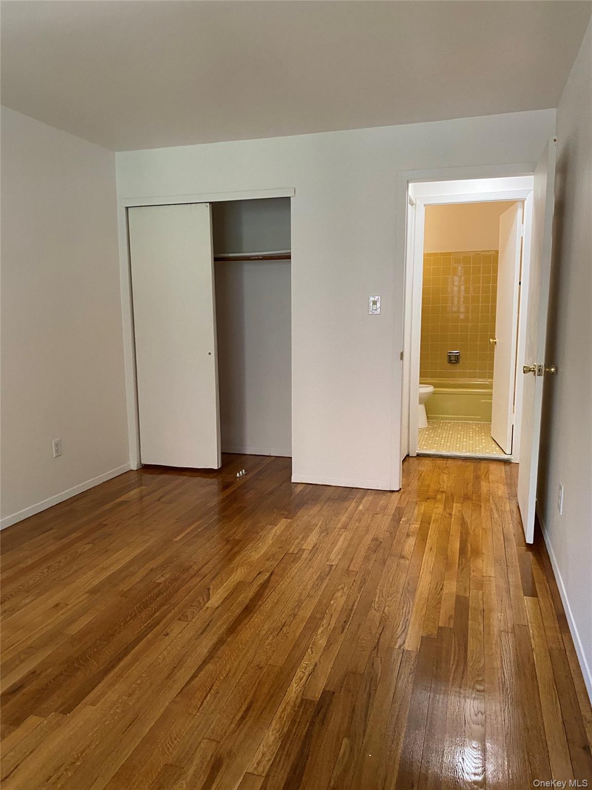 84-24 98th Street, Unit 1 Queens, NY 11421 - Photo 12 of 22 a view of an empty room with wooden floor and a bathroom
