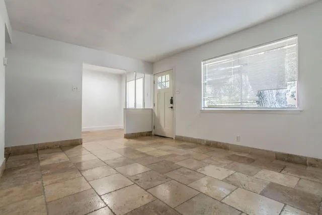 a view of an empty room with window and chandelier fan