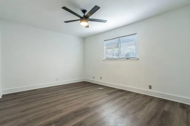 an empty room with wooden floor and a ceiling fan