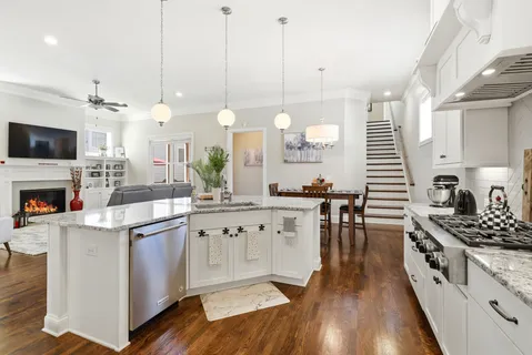 a kitchen with granite countertop a stove a sink a dining table and chairs