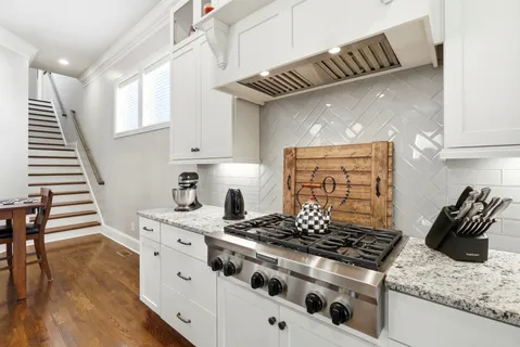 a kitchen with granite countertop a stove and white cabinets