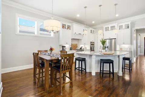 a dining room with stainless steel appliances kitchen island a table chairs and wooden floor