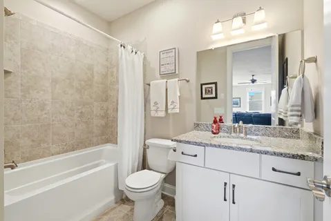 a bathroom with a granite countertop sink toilet mirror and bathtub