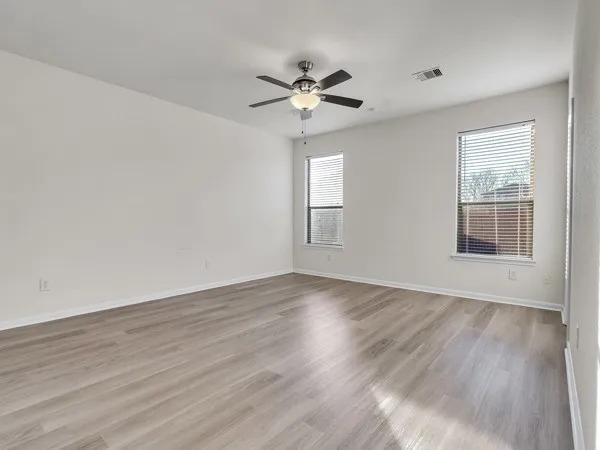 an empty room with wooden floor and ceiling fan