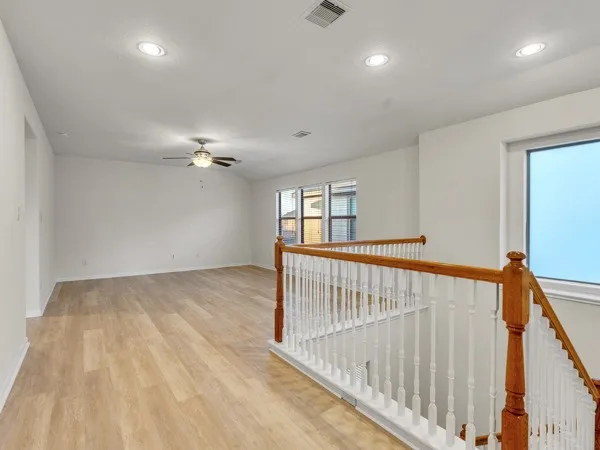 a view of an empty room with a window and wooden floor