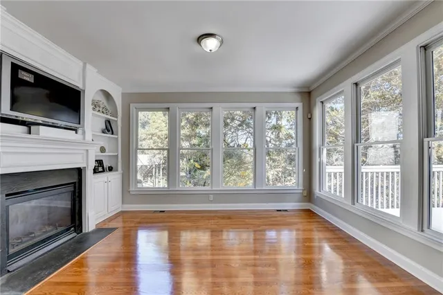 a view of an empty room with wooden floor and a fireplace