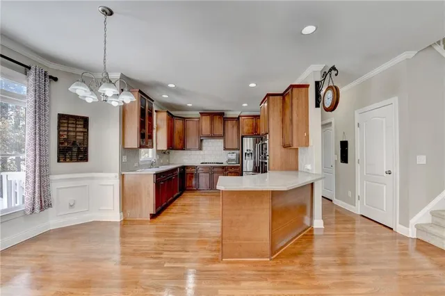 a view of a kitchen with kitchen island a counter top space appliances and a ceiling fan