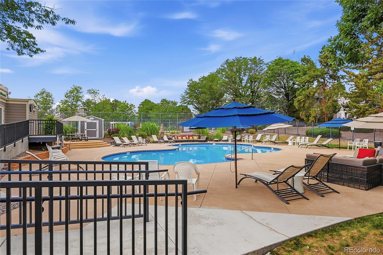 6855 West 84th Way, Unit 32 Arvada, CO 80003 - Photo 26 of 37 a view of a swimming pool with lawn chairs under an umbrella