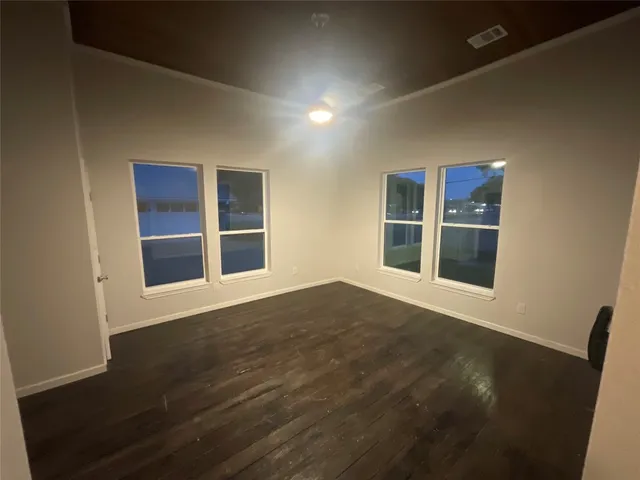 a view of an empty room with wooden floor and windows