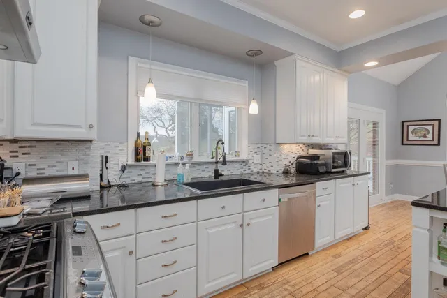 a dining room with wooden floor a chandelier a glass table and chairs