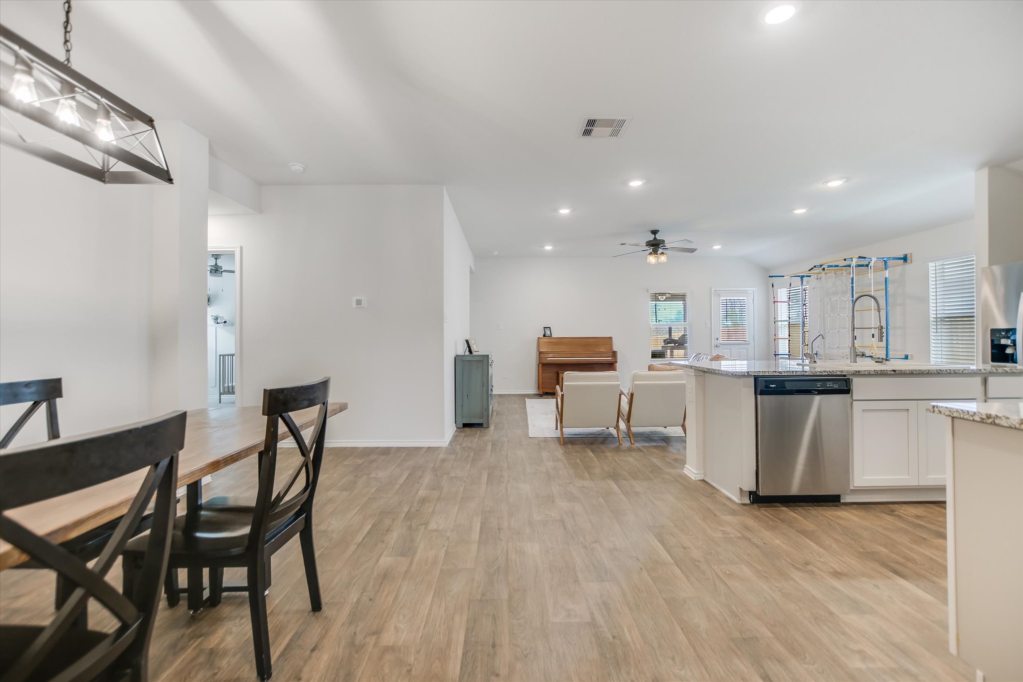 262 Sickle Loop Kyle, TX 78640 - Photo 19 of 20 Kitchen featuring stainless steel appliances, light wood finished floors, white cabinetry, open floor plan, and lofted ceiling