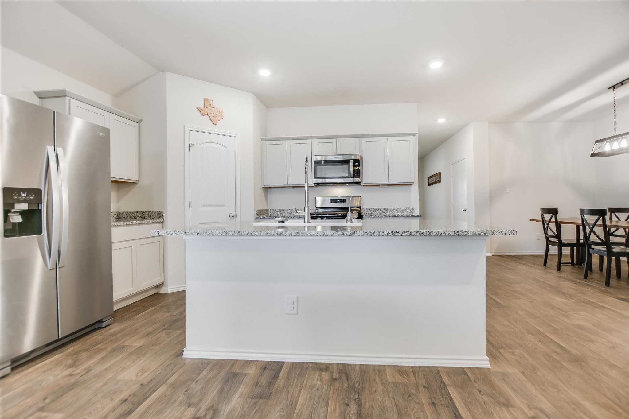 262 Sickle Loop Kyle, TX 78640 - Photo 6 of 20 Kitchen featuring stainless steel appliances, light wood finished floors, a kitchen island with sink, light stone countertops, and white cabinets