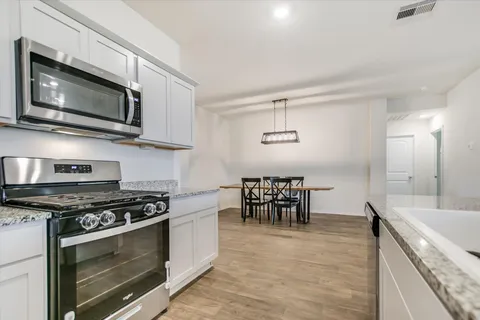 a kitchen with stainless steel appliances kitchen island wooden floors and white cabinets