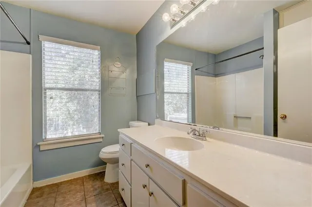 a bathroom with a granite countertop sink toilet and large mirror