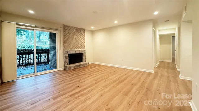 a view of empty room with wooden floor and fireplace