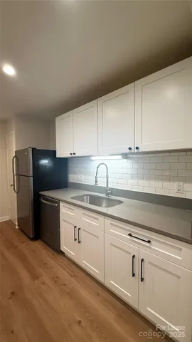 a kitchen with stainless steel appliances granite countertop a refrigerator sink and white cabinets