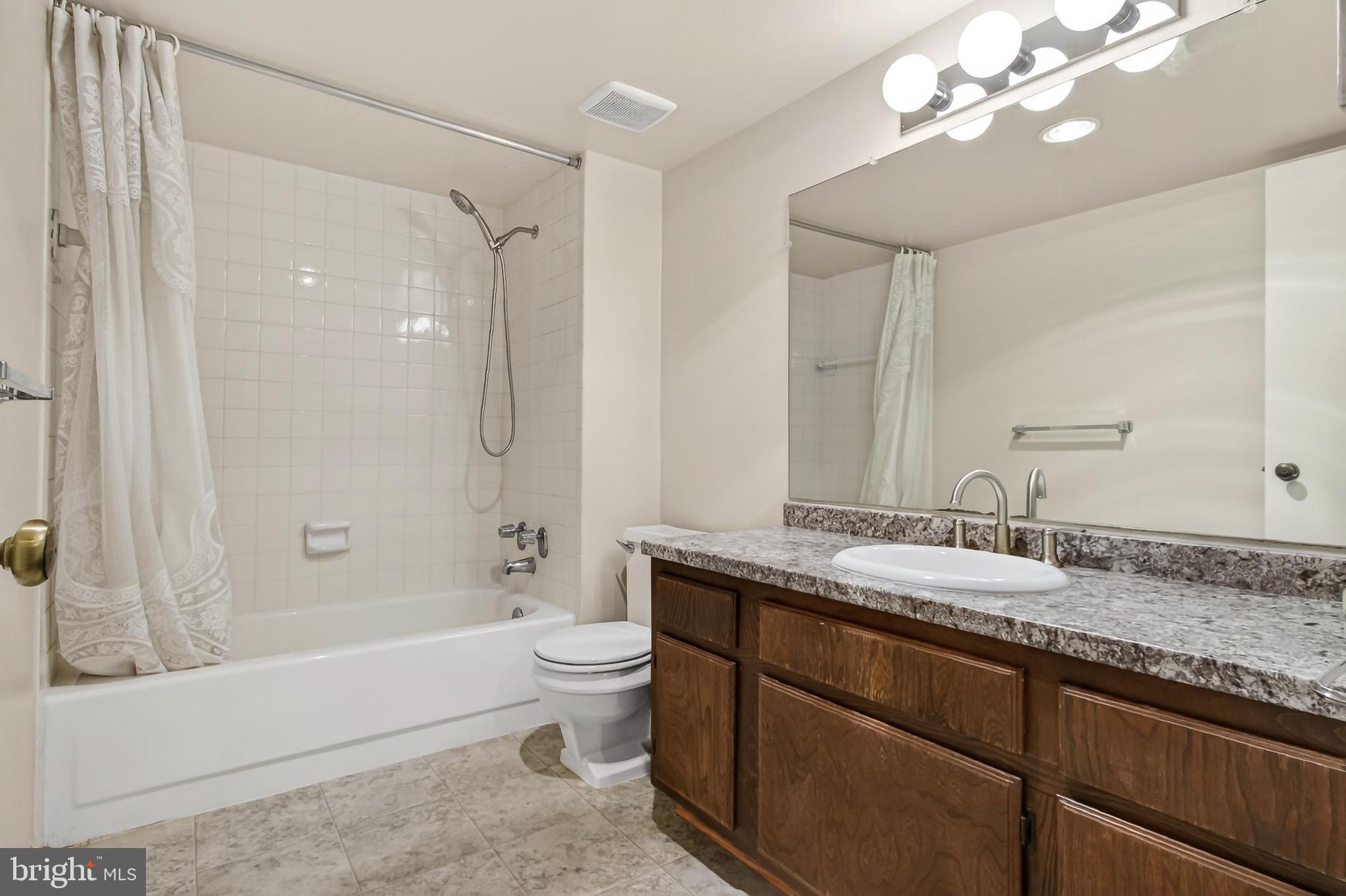 6101 Edsall Road, Unit 1206 Alexandria, VA 22304 - Photo 30 of 52 a bathroom with a granite countertop sink a toilet and bathtub