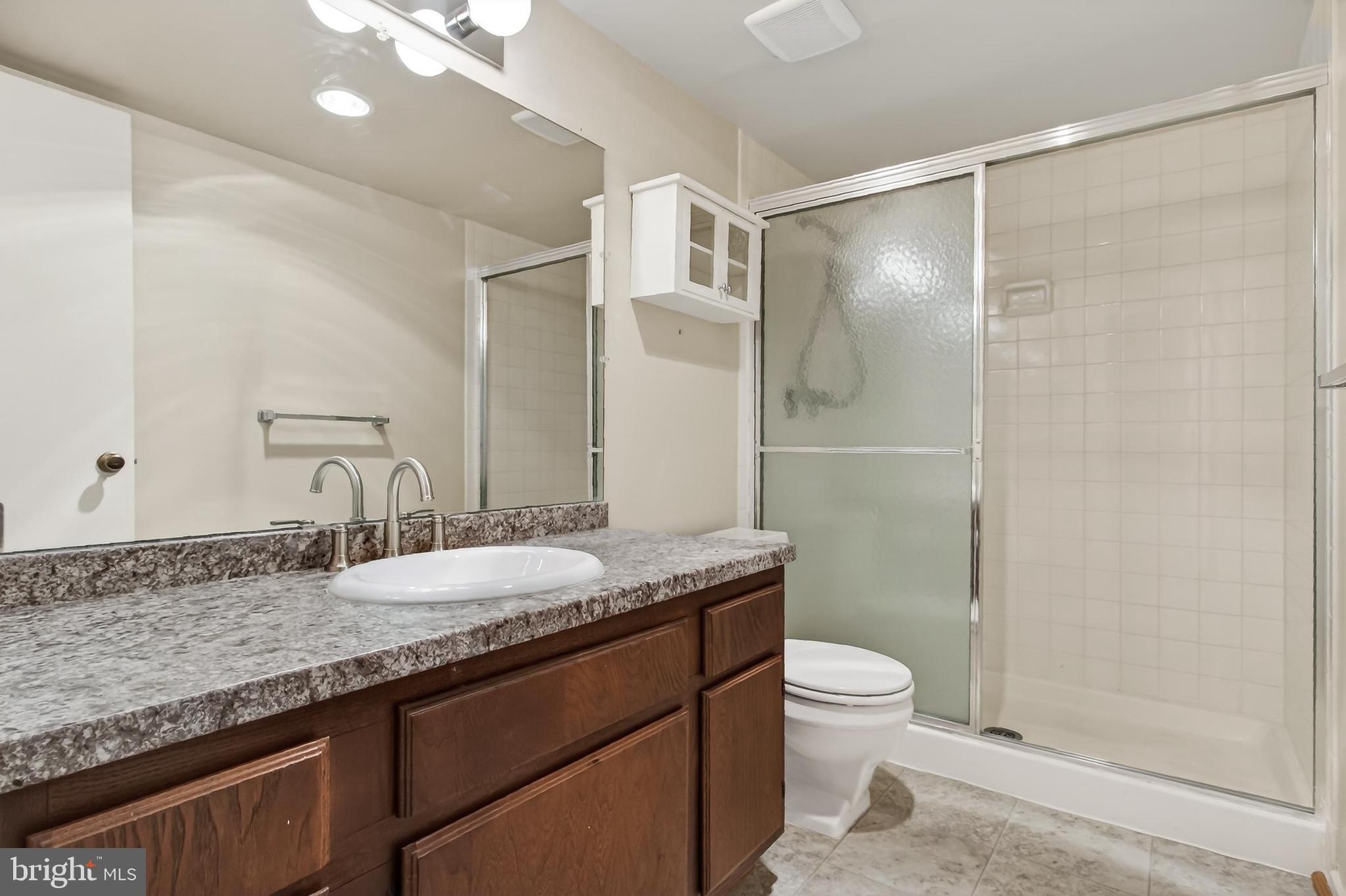 6101 Edsall Road, Unit 1206 Alexandria, VA 22304 - Photo 33 of 52 a bathroom with a granite countertop sink toilet a mirror and shower