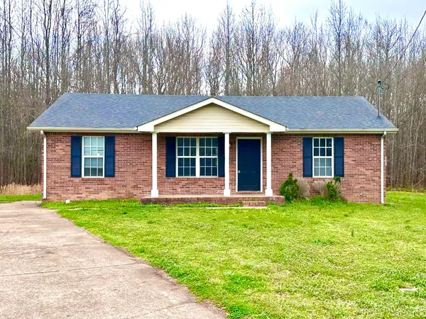a view of a house with a yard and large tree